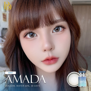 Close-up of a person with brown hair and gray AMADA contact lenses packaging.