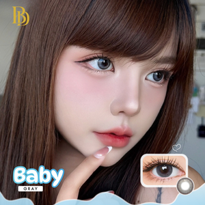 Close-up of a person with brown hair and gray eyes, wearing contact lenses labeled 'Baby Gray'.