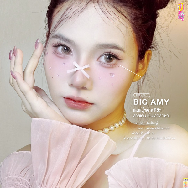 Woman with pearl necklace and pink top, holding hand to face, with 'BIG AMY' branding.