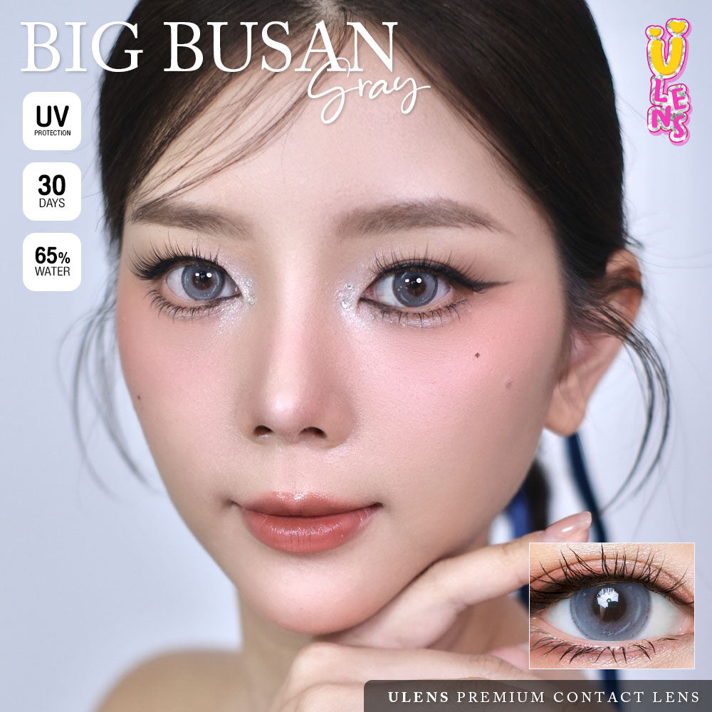 Advertisement for Big Busan gray contact lenses with a model wearing them, showing close-up of eyes and contact lens.