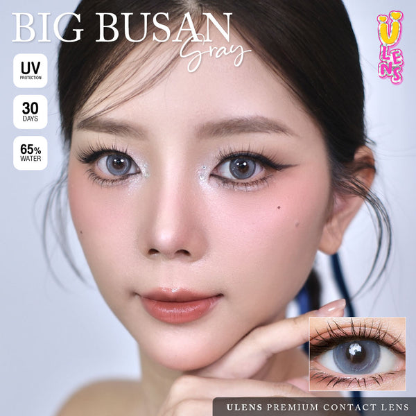 Advertisement for Big Busan gray contact lenses with a model wearing them, showing close-up of eyes and contact lens.