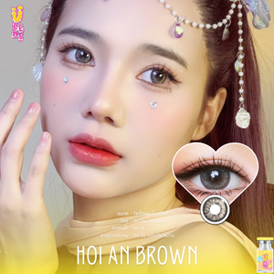 Close-up of a person with decorative hair and a heart-shaped inset showing contact lenses, with 'Hoi An Brown' text and product packaging.