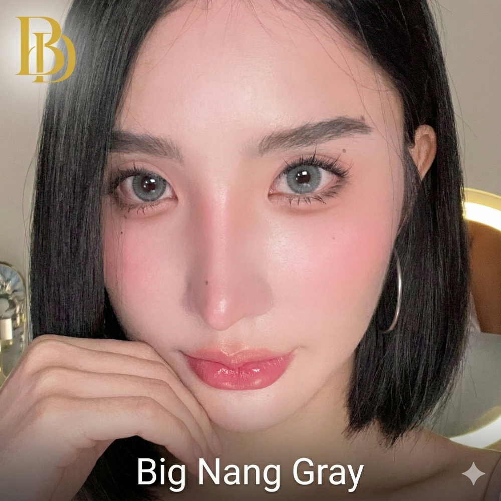 Close-up of a person with dark hair and gray eyes, wearing pink lipstick, with 'Big Nang Gray' text and a logo in the corner.