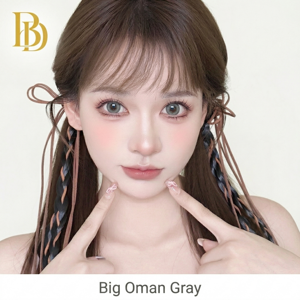 Woman with styled hair pointing to her face against a plain background