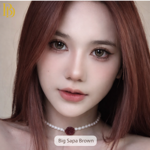 Close-up of a person with red hair wearing a pearl necklace, with 'Big Sapa Brown' branding.