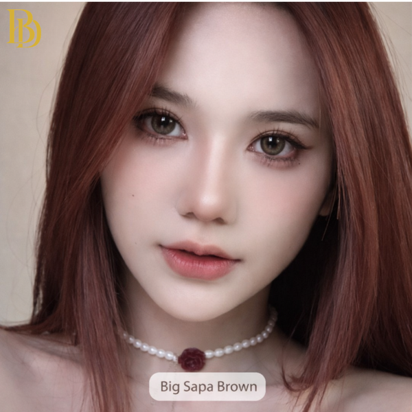Close-up of a person with red hair wearing a pearl necklace, with 'Big Sapa Brown' branding.