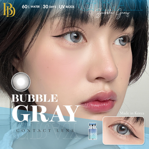 Contact lens advertisement for Bubble Gray contact lenses, showing a close-up of a model's face with blue-tinted eyes, a graphic of a gray contact lens, and text including '60% WATER | 30 DAYS | UV BLOCK' and 'Made in Korea'.