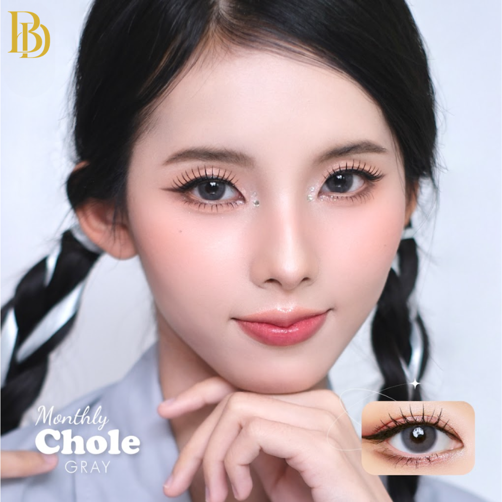 Close-up of a person wearing gray contact lenses with 'Monthly Chole' branding.