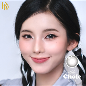 Close-up of a person with styled hair and makeup, featuring 'Monthly Chole' contact lenses.