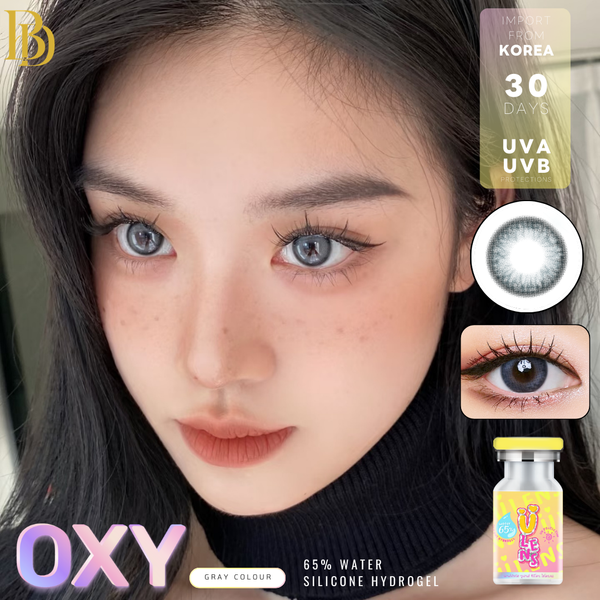 Close-up of a person wearing gray colored contact lenses with product packaging and branding visible.