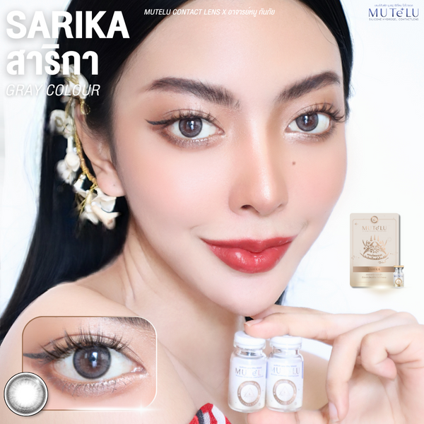 Woman holding contact lens solution with Sarika Gray contact lenses and MuteLu packaging in the background.