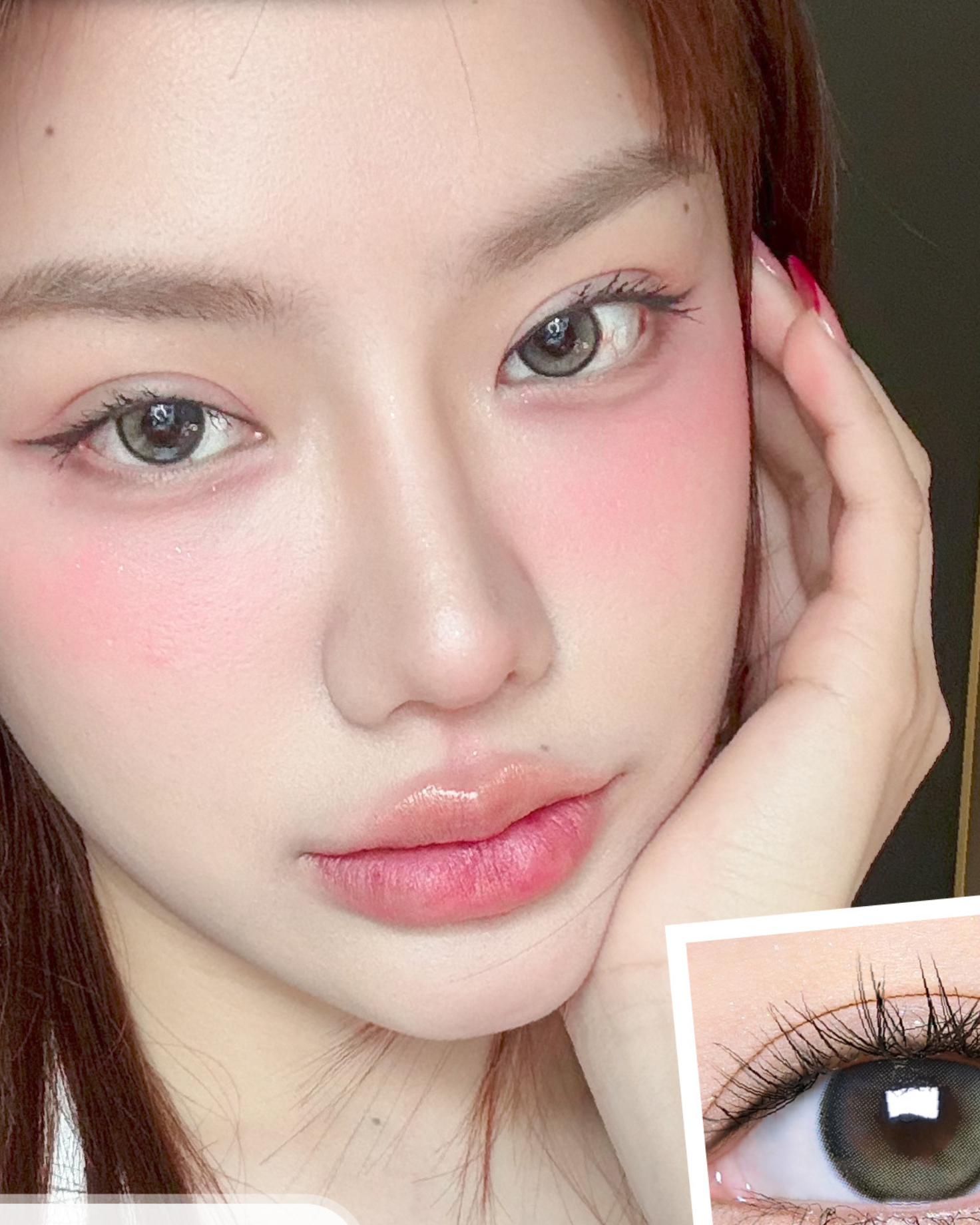 Close-up of a person's face with a hand on their cheek, wearing makeup.