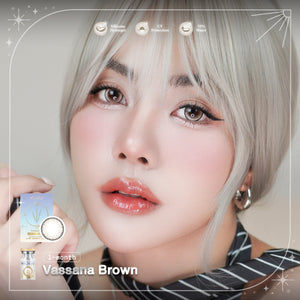 Person with platinum blonde hair holding a contact lens and contact case, with 'Vassana Brown' branding.